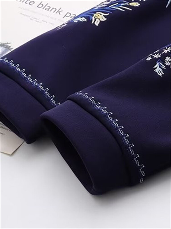 Suures suuruses naiste mantel, ümmargune kaelus, pikkade varrukatega paksendatud mantel, mille sees on plüüs, varrukatel tikitud lillemotiiv