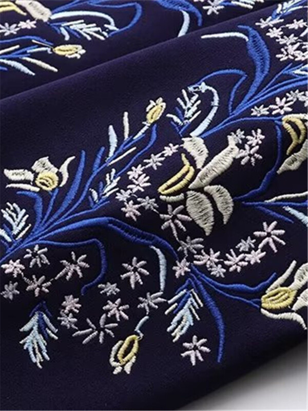 Suures suuruses naiste mantel, ümmargune kaelus, pikkade varrukatega paksendatud mantel, mille sees on plüüs, varrukatel tikitud lillemotiiv