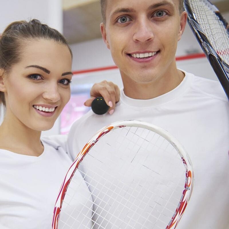 Skvošo kamuoliukas su dvigubu geltonu tašku, guminiu skvošo rakečių kamuoliuku Skvošo greičio treniruotė vienam mėlynam dvigubo geltono taško skvošo kamuoliui