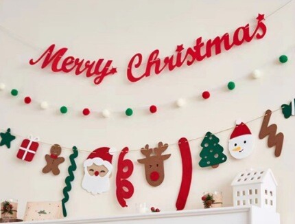 Нанизи от червени, зелени и бели помпони Коледни плюшени топки украсяват коледната елха и подреждат декорации около фона на окачената стена