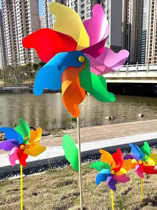 Spalvingo vėjo malūno lauko dekoravimo festivalio vaizdingas parkas, vaikai laiko besisukantį medinį spalvotą vėjo malūną