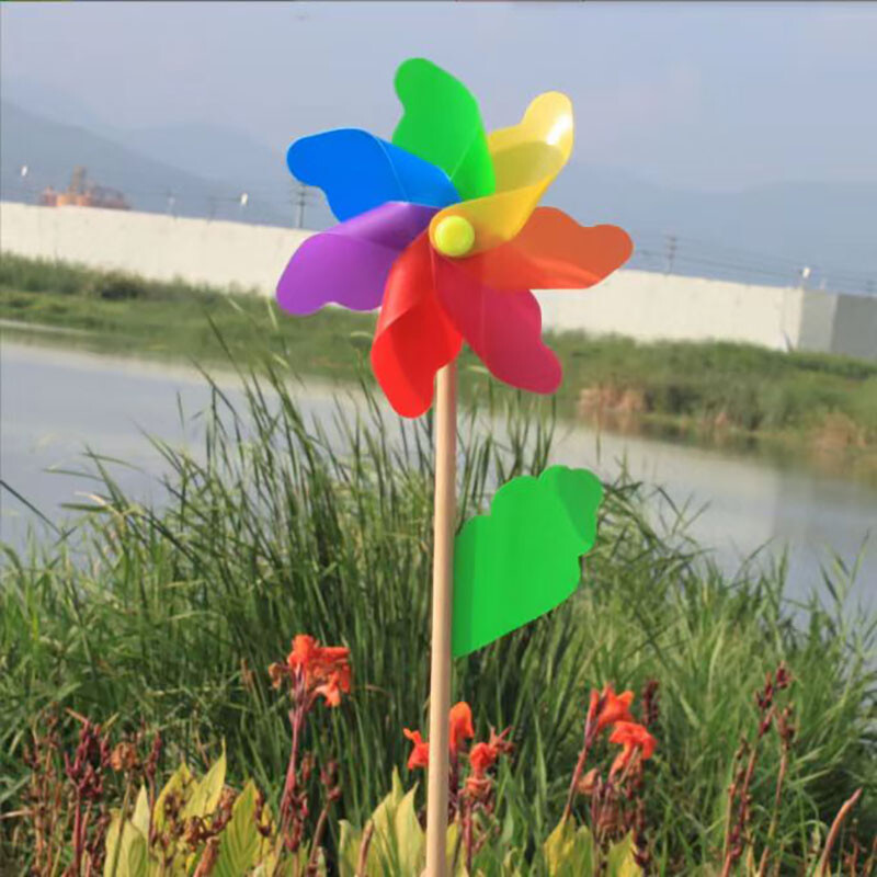 Spalvingo vėjo malūno lauko dekoravimo festivalio vaizdingas parkas, vaikai laiko besisukantį medinį spalvotą vėjo malūną