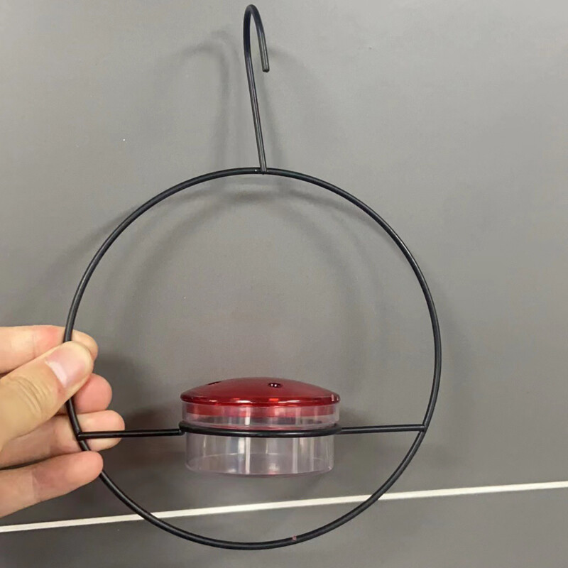 Piekarināmā kolibri barotava piesaista putnus āra kolibru barotavai ar sarkanu stikla bļodu āra dārza piemājas terases klājam